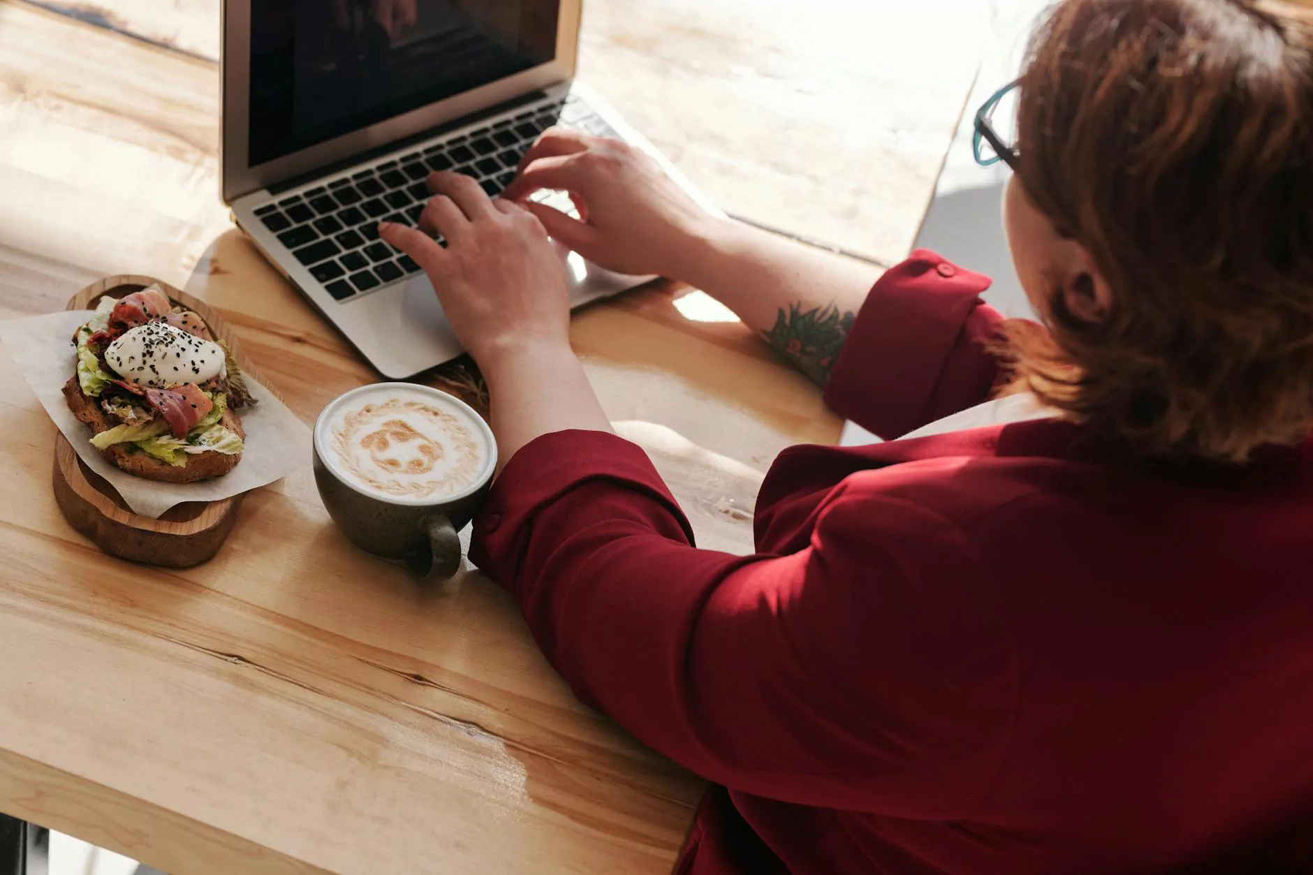 Coffee and toast beside a laptop on a wooden table