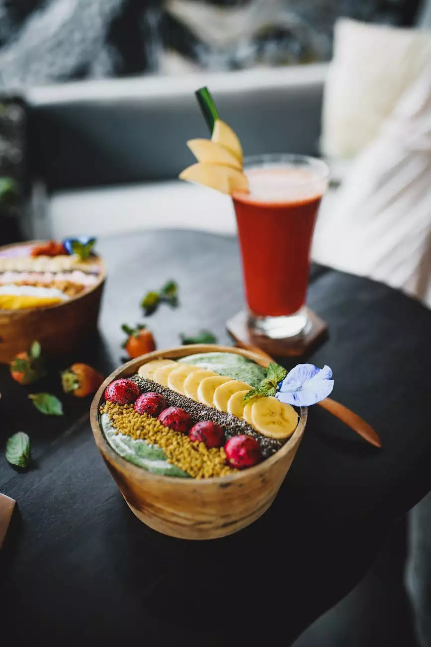 A fruit-topped bowl beside a bright red drink on a dark table